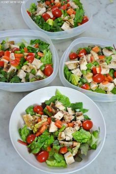 four white bowls filled with salad on top of a table