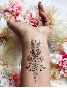 a woman's hand with a tattoo on it and flowers in the background next to her