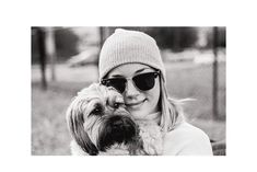 a black and white photo of a woman with sunglasses holding a dog in her lap