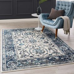 a blue and white area rug with an ornate design on the bottom, in front of a gray wall