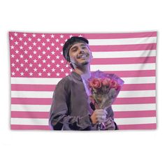 a man holding flowers and standing in front of an american flag wall hanging on a wall