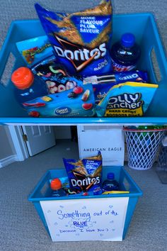 a blue bin filled with snacks sitting on the floor