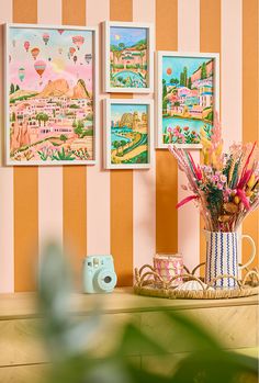 there are pictures hanging on the wall behind a vase with flowers and pencils in it