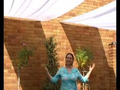 a woman standing in front of a brick wall with her arms out and hands outstretched