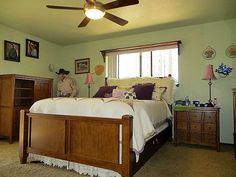 a bed room with a neatly made bed and a ceiling fan on the side of it