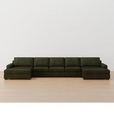 a large green couch sitting on top of a wooden floor next to a white wall