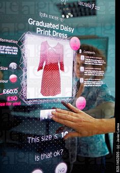 a woman looking at her cell phone in front of a display with information about the dress