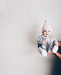 a man holding a baby wearing a pink hat and grey sweater with white trims