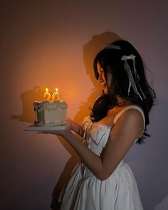 a woman holding a cake with two candles on it