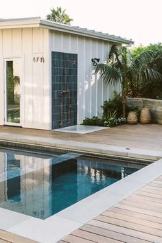 a swimming pool with a small house in the back ground and palm trees around it