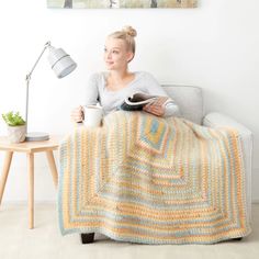 a woman sitting on a couch holding a coffee cup