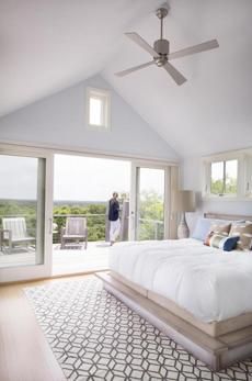 a bedroom with a large bed and sliding glass doors leading to an outdoor deck area