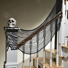 a skeleton sitting on top of a set of stairs next to a net covered staircase