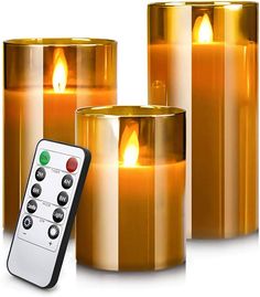 three lit candles with remote controls in front of each one on a white background,