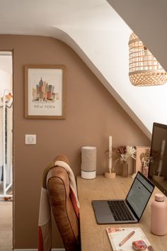 an open laptop computer sitting on top of a wooden desk next to a brown chair