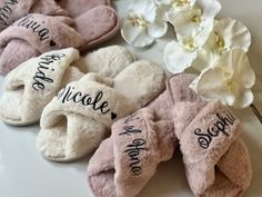 several pairs of slippers with personalized names on them next to white orchids