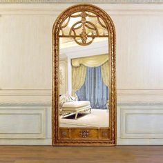 an ornate gold framed mirror in the middle of a room with white walls and wood flooring