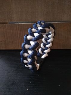 a blue and white bracelet sitting on top of a black table next to a wooden wall