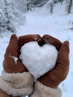 someone is holding up a heart shaped snowball