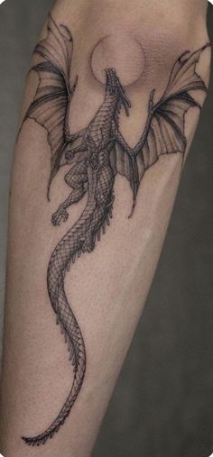 a black and grey dragon tattoo on the leg