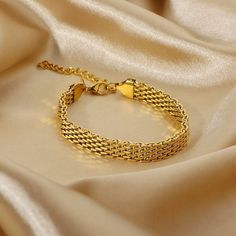 a gold chain bracelet laying on top of a white cloth