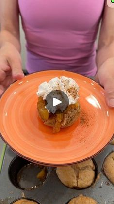 a person holding an orange plate with some food on it and muffins in the background