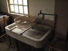 a sink with a basket sitting on top of it in a room next to a window