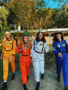 four girls in space suits are walking down the street together and one girl is wearing a party hat