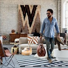 a man walking through a living room with lots of furniture and accessories on the floor