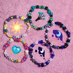 four bracelets with different designs on them sitting on a pink towel next to each other