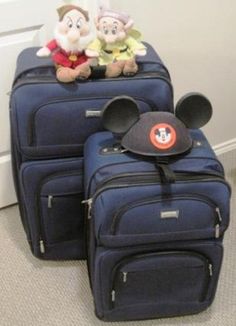 two suitcases with mickey mouse ears on them and one has a stuffed animal in the middle