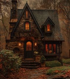 a small stone house in the woods at night with lights on it's windows