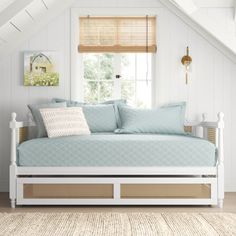 a white daybed with blue sheets and pillows in a room under a slanted ceiling