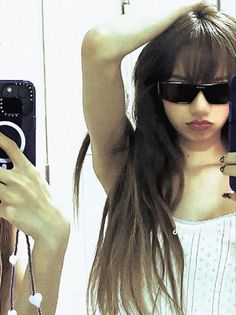 a woman with long hair and sunglasses taking a selfie in front of a mirror