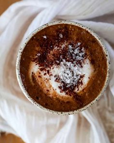 an overhead view of a cup of hot chocolate with powdered sugar and cinnamon on top