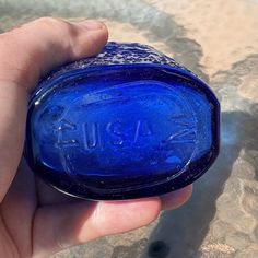 a hand holding a blue glass bottle with the word aqua on it's side