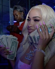 a woman holding cash in her hands and wearing pink nail polish on the other hand