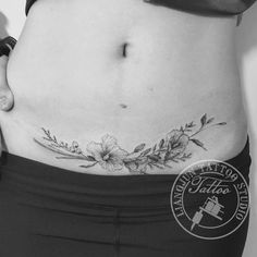 a woman's stomach with flowers and leaves on the side, in black and white