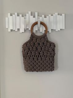 a crocheted purse hanging on the wall with white pegs attached to it