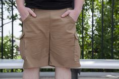 a man standing in front of a white bench with his hands on his hips and wearing brown shorts