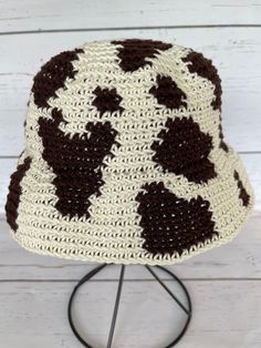 a crocheted hat is sitting on top of a metal stand with a white background