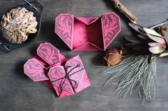 three origami boxes sitting on top of a table next to flowers and branches