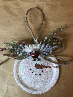 a snowman ornament hanging from a string on a brown paper bag with twine