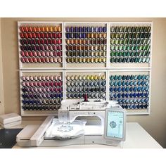 a sewing machine sitting on top of a table next to a shelf filled with different colored spools