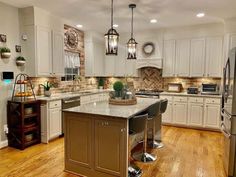 a large kitchen with white cabinets and wood flooring, an island in the middle