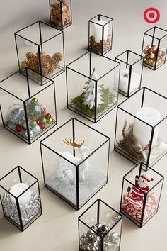 a group of glass cubes filled with different types of christmas decorations and candles on top of each other