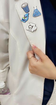 a person in a white jacket with some stickers on their lapel and buttons