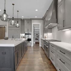 a large kitchen with gray cabinets and white counter tops