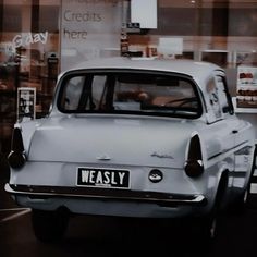 an old white car is parked in front of a store window with the words westly on it