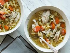 two bowls of chicken noodle soup on a marble table